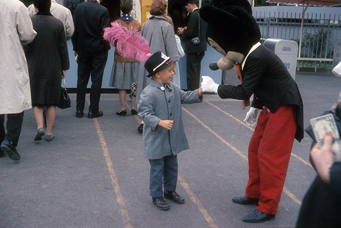 Boy in feathered hat meets Mickey Mouse